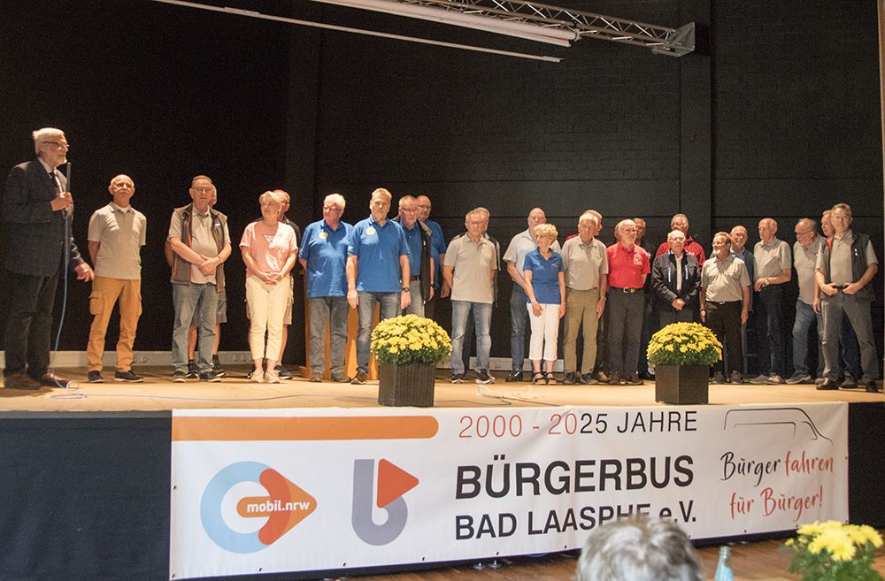 26 Bürgerbusfahrer*innen auf einer Bühne.