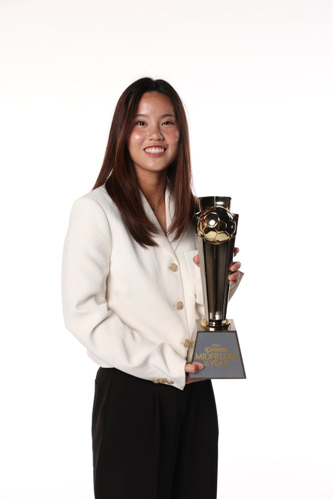 Manaka smiles holding the Midfielder of the Year trophy