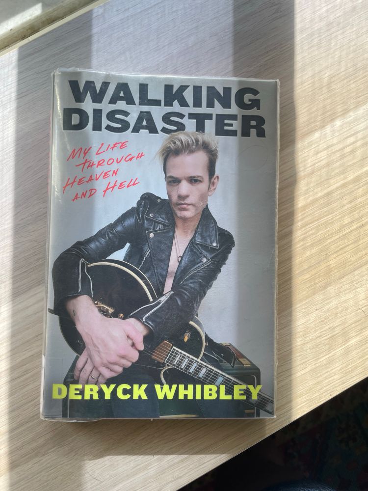 Walking Disaster by Deryck Whibley rests on a shelf. The cover features a photo of the author holding a guitar. 