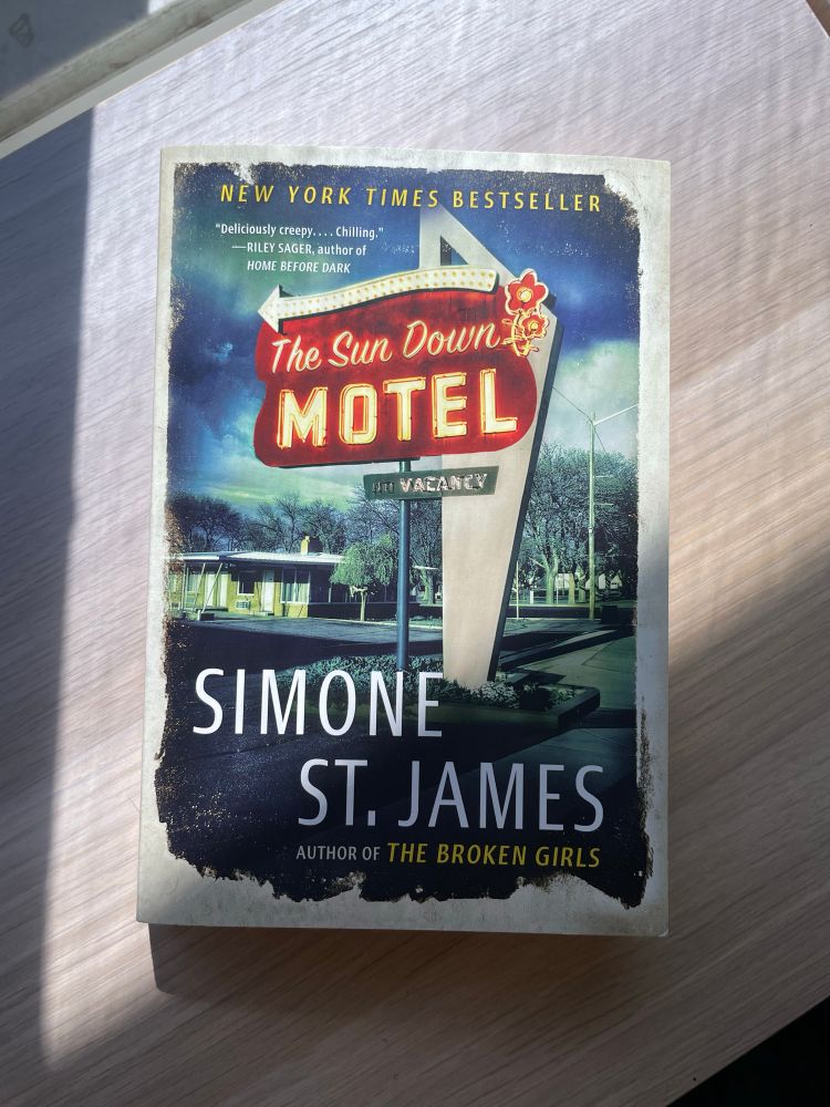 The Sundown Motel by Simone St. James rests on a sun dappled shelf.