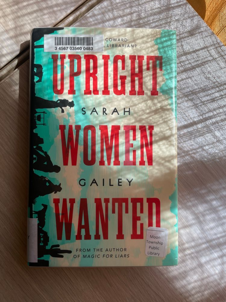 Upright Women Wanted by Sarah Gailey sits on a sun dappled shelf.