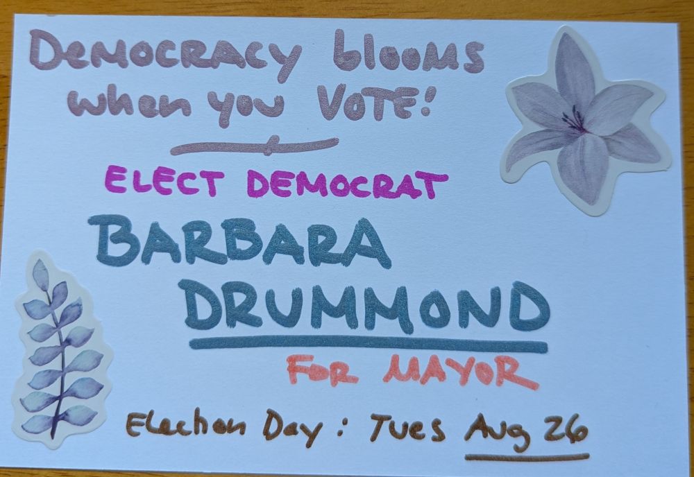 Postcard says democracy blooms when you vote. Elect Democrat Barbara Drummond for Mayor. Election day is Tuesday August 26. 
