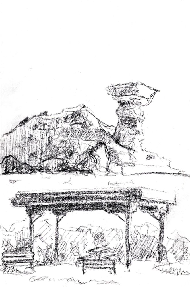 Conte crayon on paper drawing of Camel Rock formation north of Santa Fe New Mexico. In the foreground is a roadside covered picnic table and in the background is a drawing of the camel shaped rock.