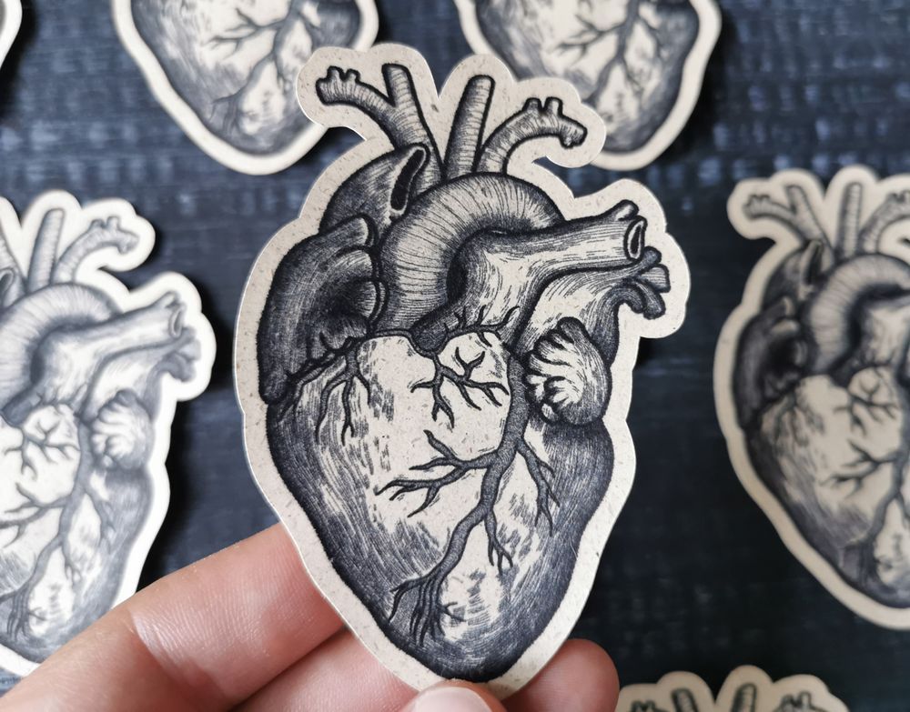 Eine Hand hält den erwähnten Sticker über mehre auf dunklem Hintergrund liegende Sticker.