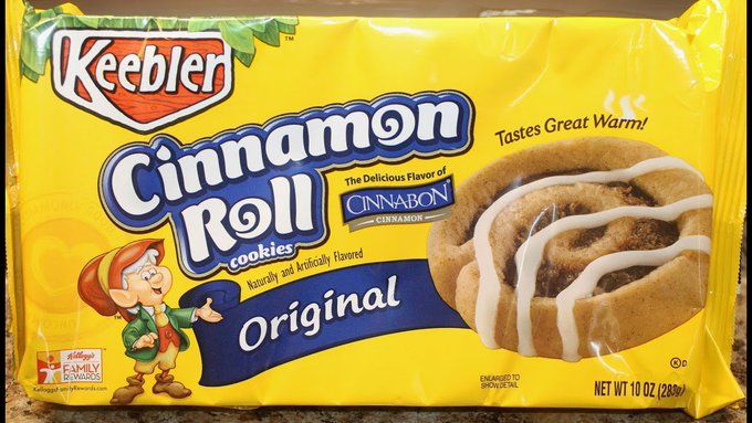 A yellow bag with the Keebler logo and Ernie the elf standing next to a cinnamon roll-shaped cookie, covered in icing. The bag reads "Cinnamon Roll cookies--tastes great warm!" next to the "Cinnabon" logo