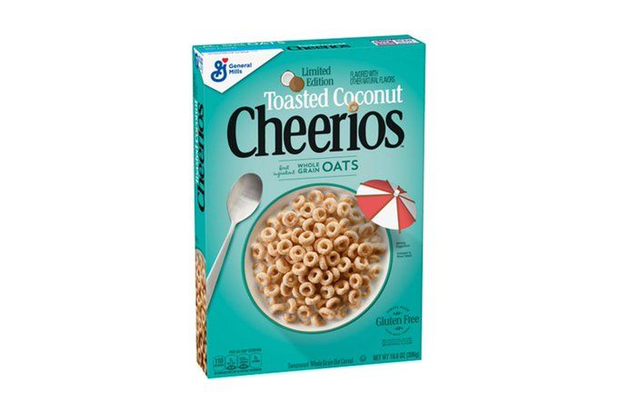 A turquoise cereal box with the image of a bowl of Cheerios, in which a red and white beach umbrella is stuck. Above it are the words "Toasted Coconut Cheerios" and the image of a coconut cut in half