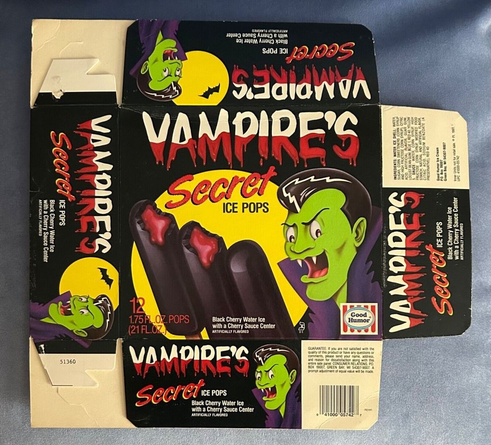 A folded cardboard popsicle box. It is black with the words "Vampire's Secret Ice Pops" written in white and red, to give the appearance of blood being drained out. There is an image of a green vampire with a pompadour and big fangy grin, next to 3 purple ice pops, open at the top to reveal a red gooey center