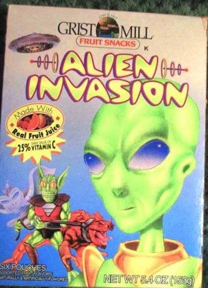 A box that reads "Grist Mill Fruit Snacks" and then "Alien Invasion" in a sort of nuclear-era cosmic font. There is a large image of a classic "little green man"-type alien next to a green goblin-type creature, holding a huge red lizard on a leash