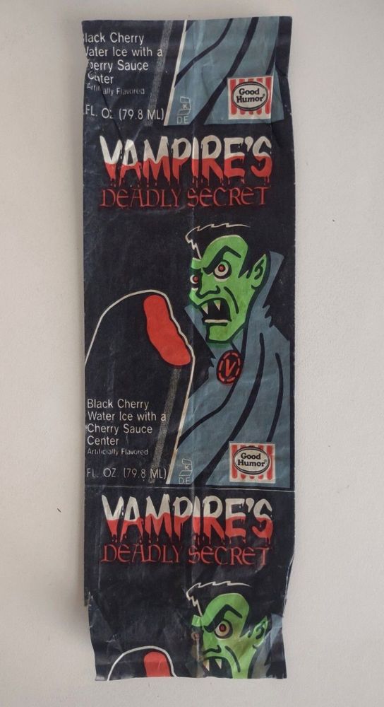 A wrapper that reads "Vampire's Deadly Secret" in red and white gothic-style font, with the appearance of "blood" being drained from it. There is an image of a green vampire with a pompadour and black cape, wearing a badge with a red "V" on it. He has a look of annoyance on his face