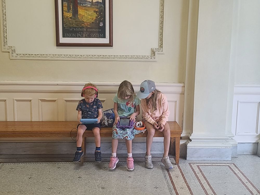 Three kids quietly hanging out while dad visits an archive. 