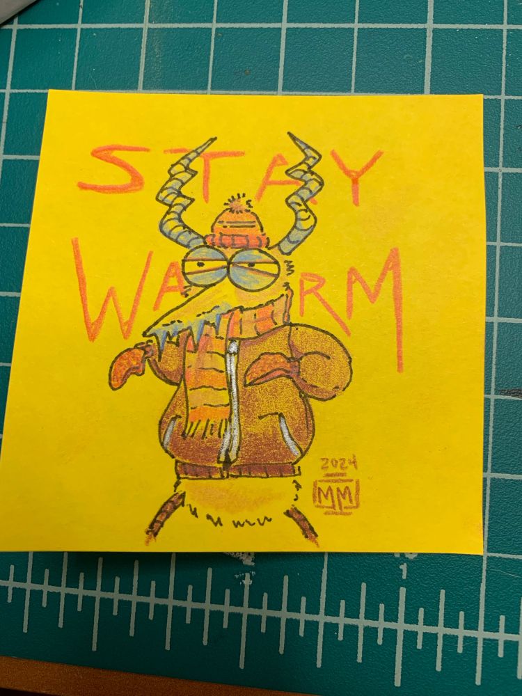 A yellow post it note. Drawn on it is a gremlin, a fuzzy creature with horns, big eyes and a beak. The gremlin is wearing a hat, scarf and coat. The gremlin’s eyes are partially closed and its beak has icicles on it. In the background is red text saying “Stay Warm”. The artist signature of MM is on the bottom right with 2024 written above it.