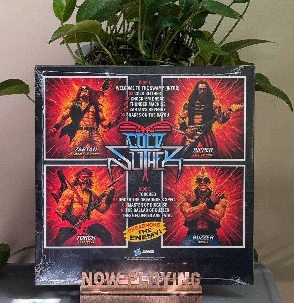A record album in a stand on a table with a plant behind it. 
