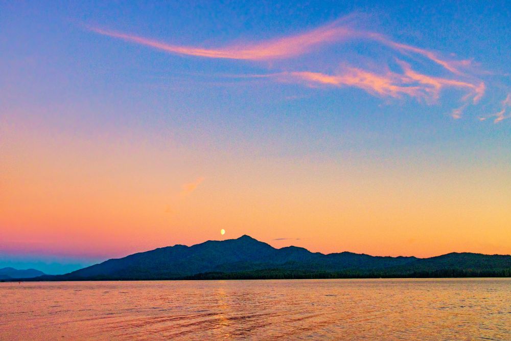 Moon rise during colorful sunset over island in Southeast Alaska