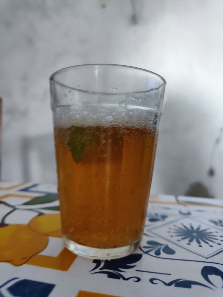 Sobre a mesa um copo americano com cerveja e um pedaço de limão 