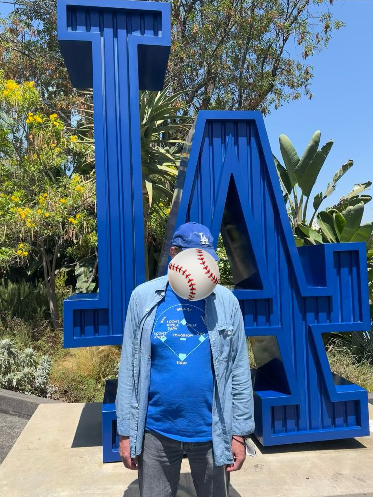 A man wearing LA ball cap, a Who’s On Forst tee shirt stands in front of the LA