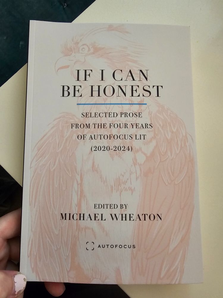If I Can Be Honest, anthology from Autofocus Books edited by Michael Wheaton, cover with bird outline, held by hand with chipped nail polish against white desk. 