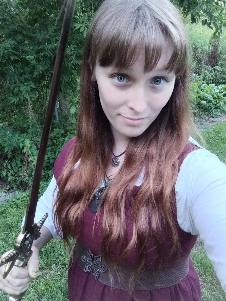 Me wearing a maroon dress over a white blouse holding my new sword (an old but very sharp sword from a garage sale today)