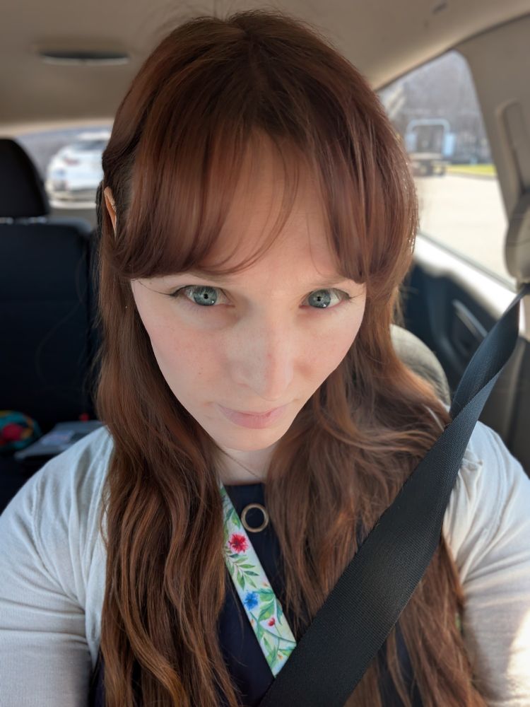 Me sitting in the car, professional outfit, blue dress, white cardigan, long reddish hair, blue eyes with yellow central heterochromia 