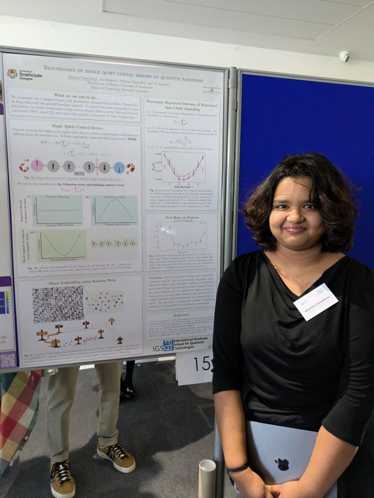 woman with brown skin in  black top with white name badge on right of poster with blue poster board behind her