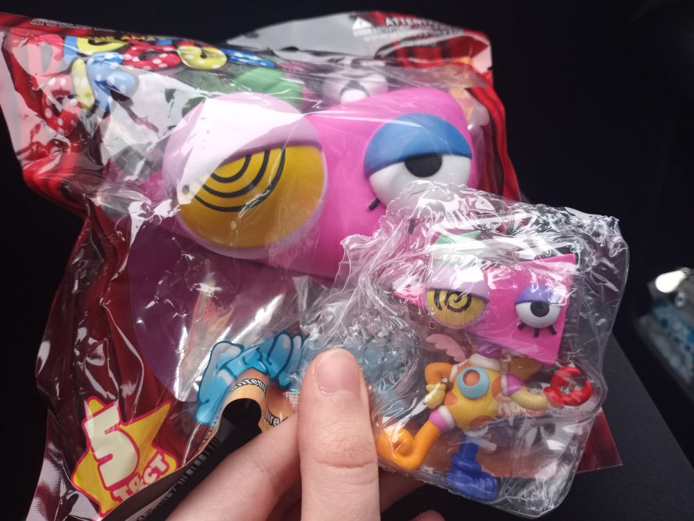 Me in the passenger seat of my mom's car, holding a Zooble SquishMe and unboxed but wrapped Zooble AniMiniz figurine