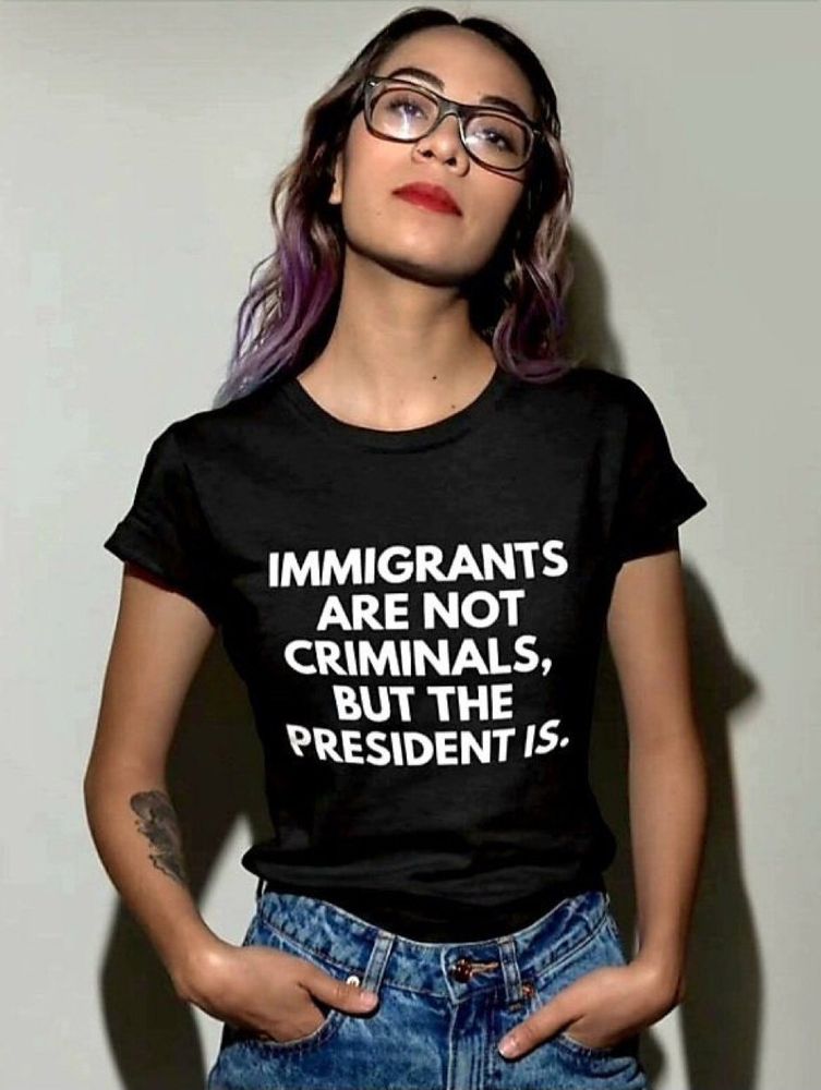 Woman wearing a T-shirt that reads immigrant are not criminals, but the president is. 