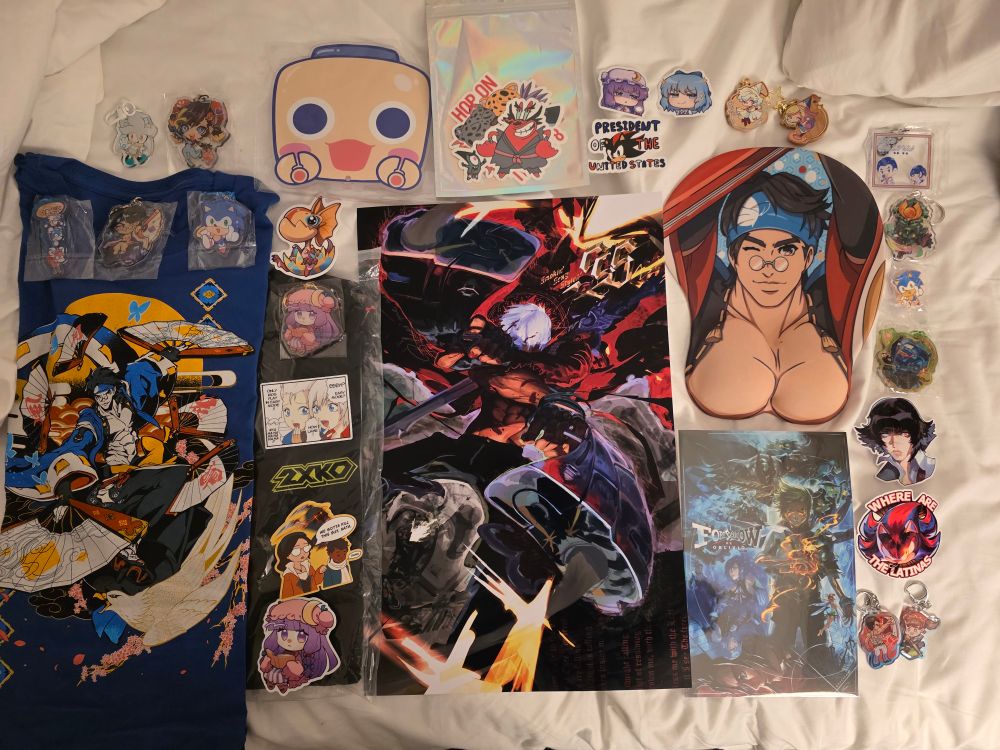 Artist Alley haul that consist of Anji shirt and mouse pad, shadow stickers, patchy sticker and keycharm, Yoshi keycharm, witch hat atelier wooden charms, lavirgobonita stickers, servbot fan, and dmc3 Dante poster
