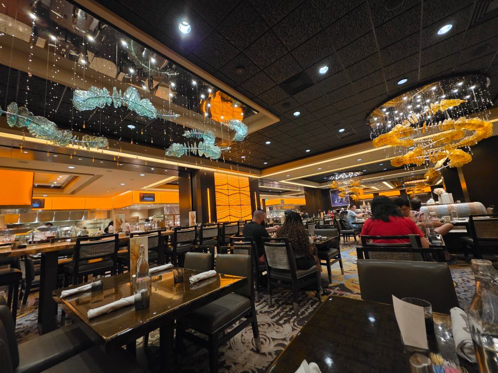 Wicked Spoon seating area with crystal fish, ceiling fixtures and rows of food in the distance 