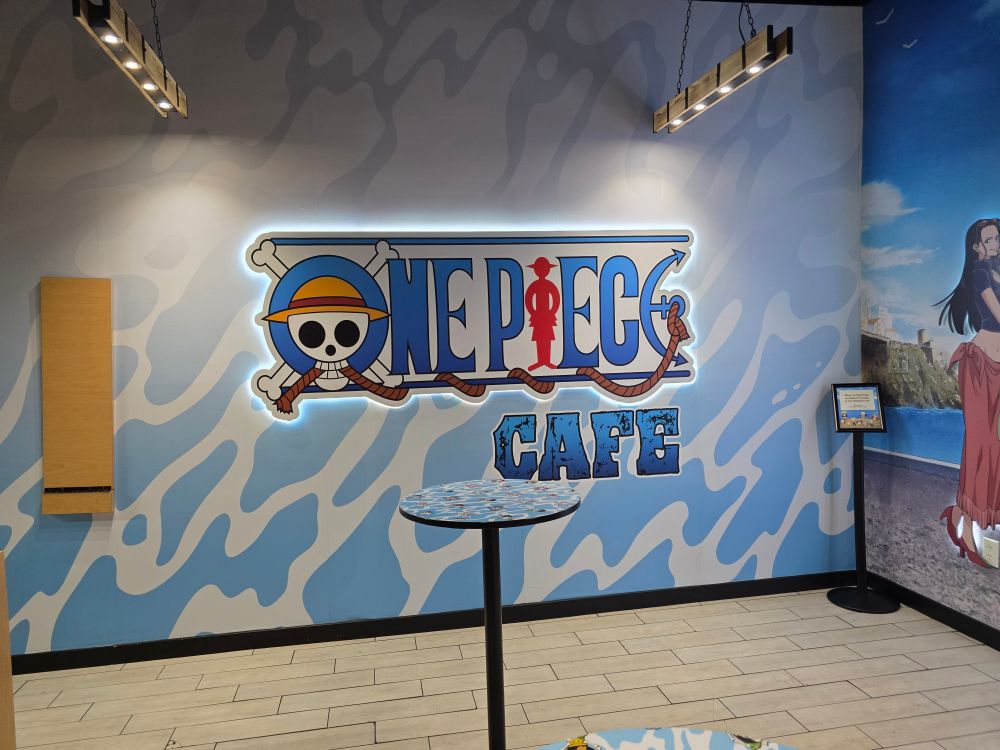 One Piece Cafe signage with water foam as a backdrop