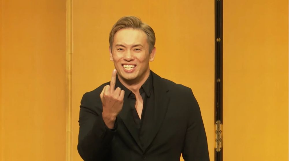 A smiling Kazuchika Okada giving everyone the middle finger. 