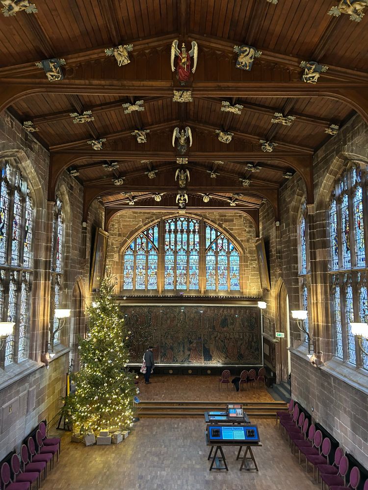 The main hall of Coventry Guildhall. The ceiling is decorated with numerous bosses and the end of the room is dominated by a 500 year old tapestry.