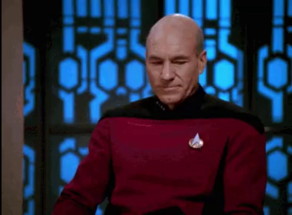 a bald man is wearing a red sweater with a star trek logo on it