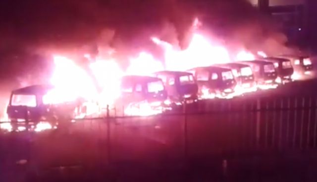 Foto der in einer Reihe abgestellten und lichterloh brennenden Autos.