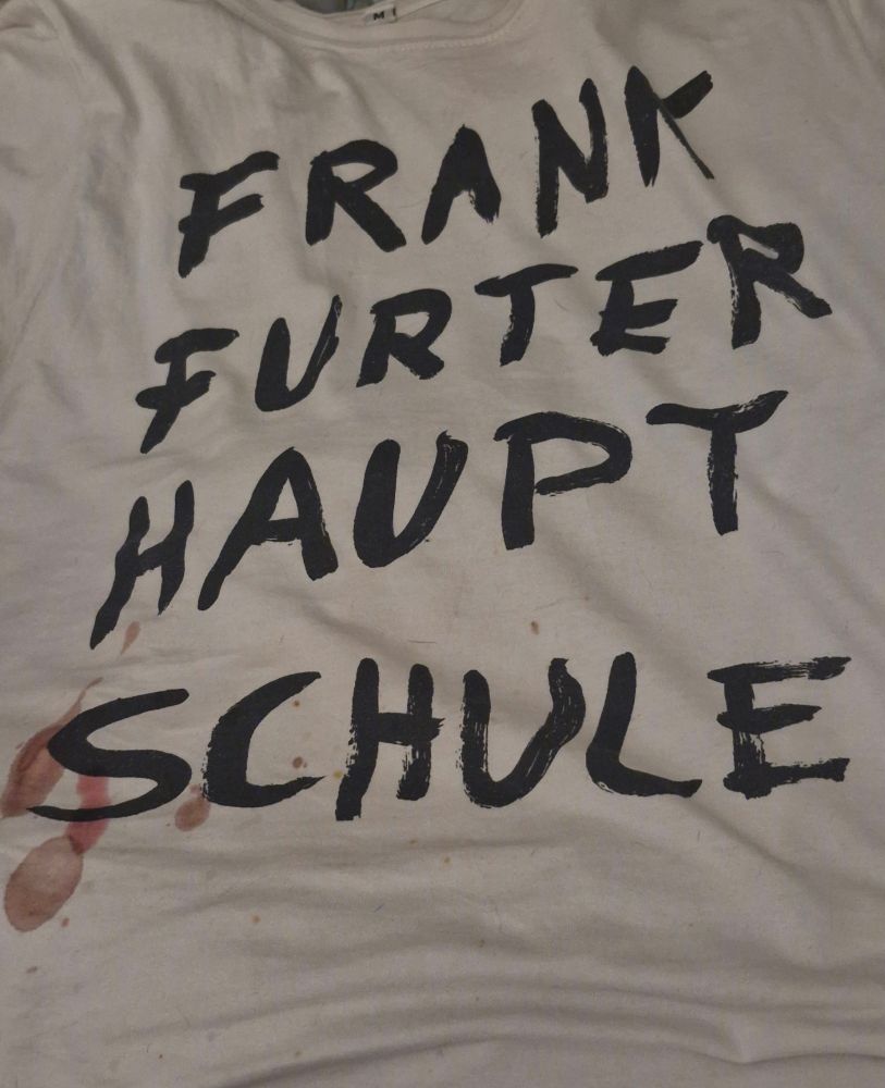 Weißes Shirt von der und mit dem Aufdruck Frankfurter Hauptschule, am Rand das Menstruationsblut des Dackels.