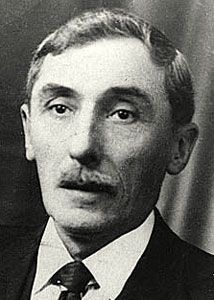 Portrait von Le Gall. Er trägt zum dunklen Anzug ein weißes Hemd und eine Krawatte und einen schmalen Oberlippenbart.