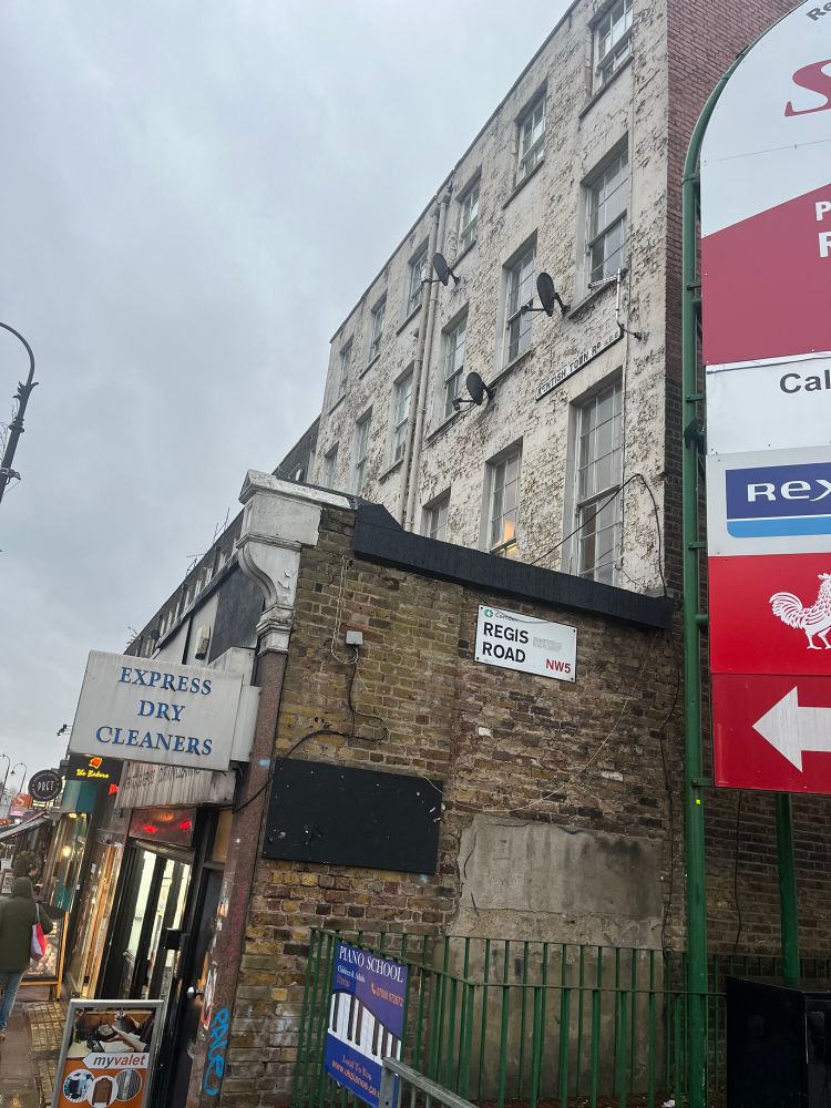 A terrace house in three storeys in bad nick with a dry cleaners underneath it.