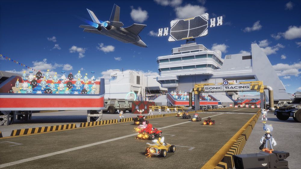 An image from a track in Sonic Racing CrossWorlds, based on Metal Harbor from Sonic Adventure 2. E-123 Omega, Knuckles Tails, Shadow, Eggman, and Zazz are the six competitors. The create-a-characters from Sonic Forces stand on the side of the track, while a collection of Neutral, Hero, and Dark Chao watch from the stands. 