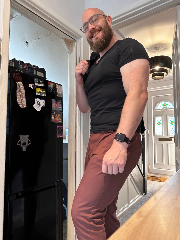 Kit wears a black shirt and red pants in his kitchen.