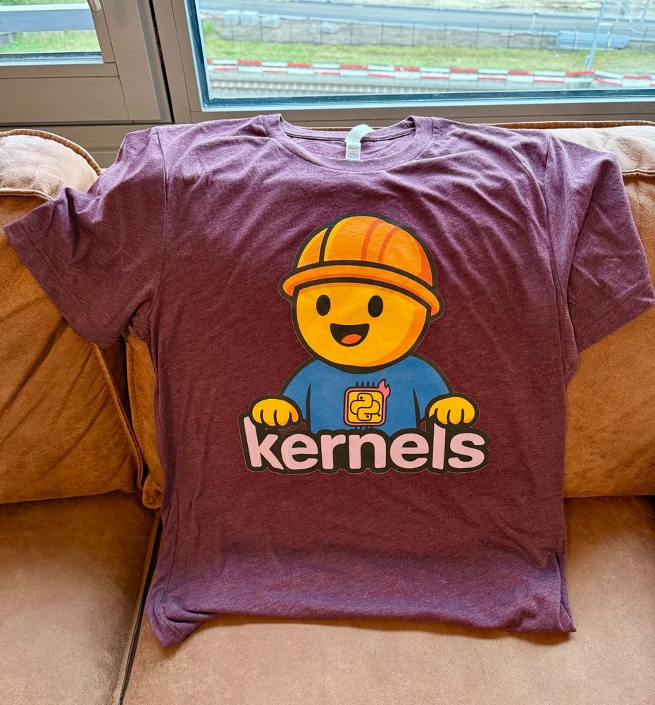 A T-Shirt with a hugging face emoji with a construction hat and the text 'kernels'.