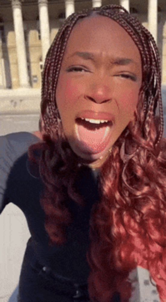 a woman with braids is making a funny face with her tongue out