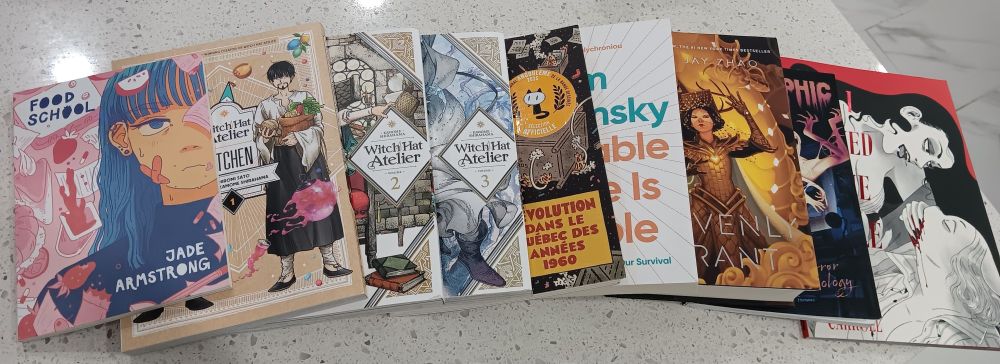 A lineup of books including: "Food School" by Jade Armstrong, "Witch Hat Atelier" (vol. 2-3 and kitchen) by Kamome Shirahama, "Mourir pour la cause: Révolution dans le Québec des années 1960" by Chris Oliveros, "A Livable Future is Possible" by Noam Chomsky, "Heavenly Tyrant" by Xiran Jay Zhao, "Polymorphic: A Horror Anthology vol. 2", "When I Arrived at the Castle" by Emily Carroll
A lineup of books including: "Food School" by Jade Armstrong, "Witch Hat Atelier" (vol. 2-3 and kitchen) by Kamome Shirahama, "Mourir pour la cause: Révolution dans le Québec des années 1960" by Chris Oliveros, "A Livable Future is Possible" by Noam Chomsky, "Heavenly Tyrant" by Xiran Jay Zhao, "A Horror Anthology vol. 2" from Polymorphic Magazine, "When I Arrived at the Castle" by Emily Carroll