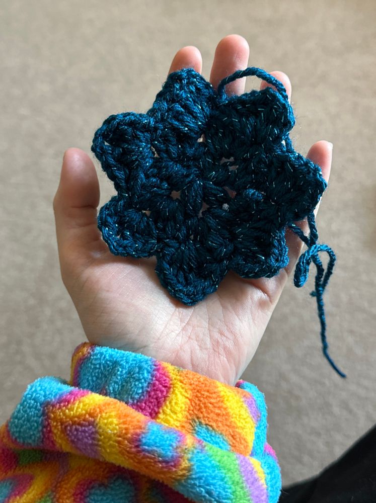 Me holding a crochet flower that was supposed to be a five point star ⭐️ 