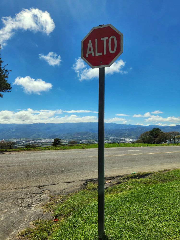 A stop sign on a mountain road with a beautiful valley in the background 