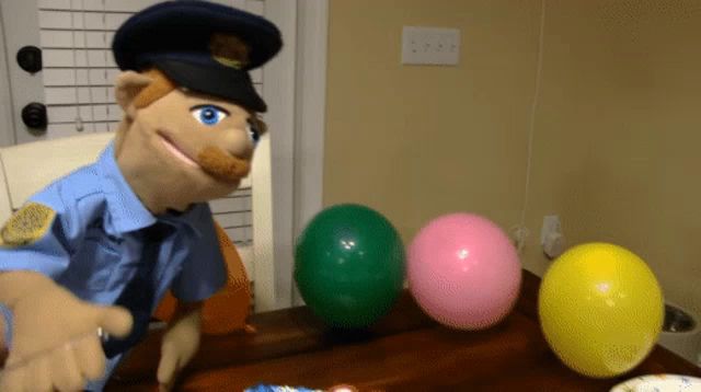 a police puppet is sitting at a table with three balloons