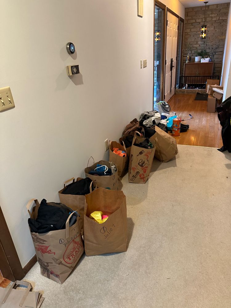 About 8 brown bags of gently used children’s clothing, sorted by size.