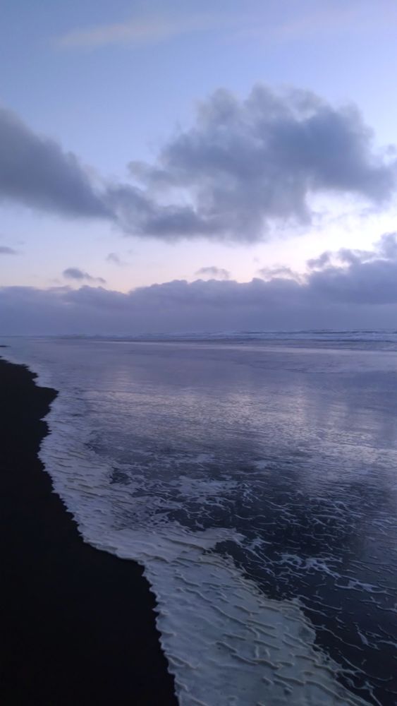evening hail falls from cloudy purple blue skies onto pacific ocean waves