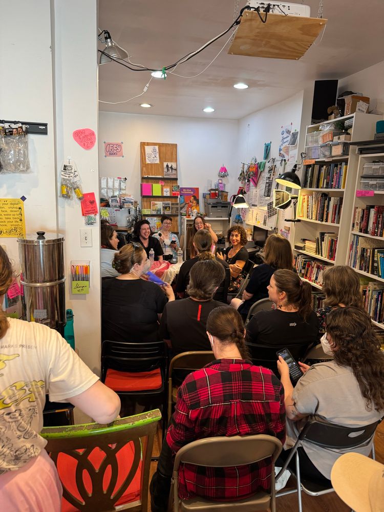 Crowd of people sit in a bookstore listening to a panel discussion. 
