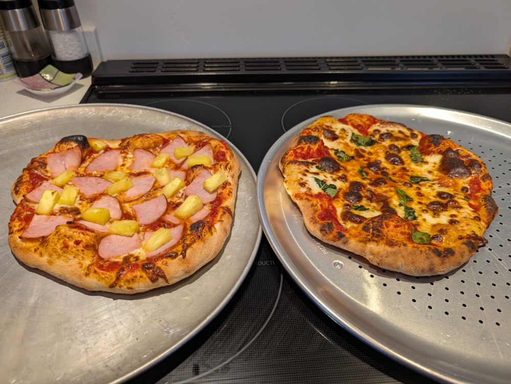 Photo of two small pizzas side by side on baking sheets. The left has ham and pineapple topping while the right is a margherita.