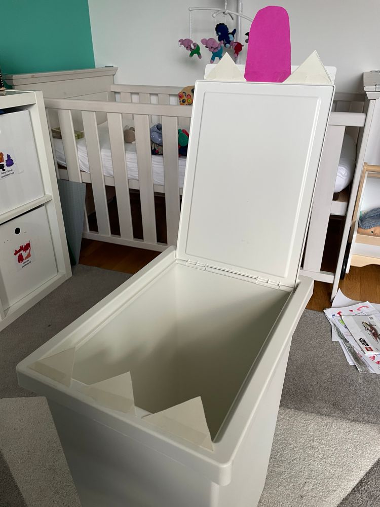 Photo of an open IKEA laundry container we stuck a cardboard tongue and carboard teeth on. 