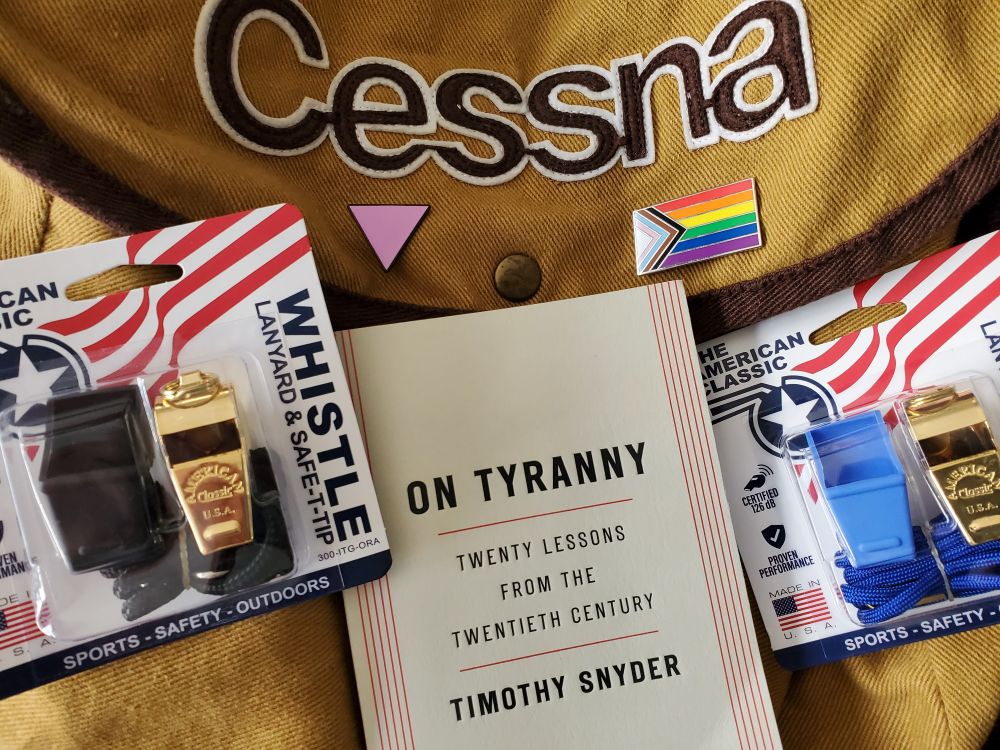 Cessna bag with a pink triangle to remind me of what has happened in the past; whistles; and the book On Tyranny by Timothy Snyder 