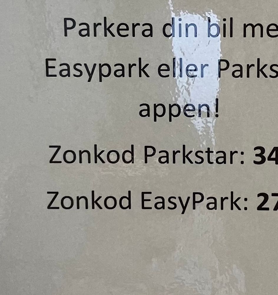 Skylt med instruktioner hur man betalar parkering via appar. Ordet zonkod förekommer. 